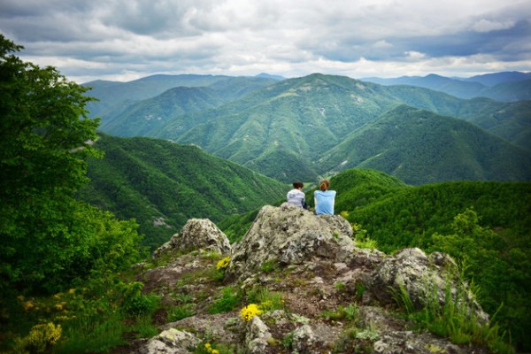 Friends sitting on rock looking at mountains